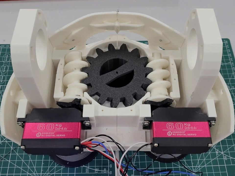 The waist module on a cutting mat: two red 60 kg servos at the front drive worm gears either side of a large black central gear.