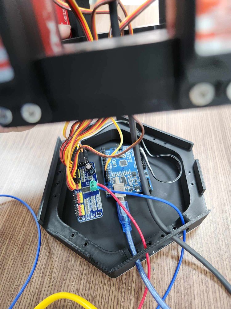 The open base: a blue PCA9685 servo board and an Arduino Uno, with servo leads and a USB cable, under the servo plate.